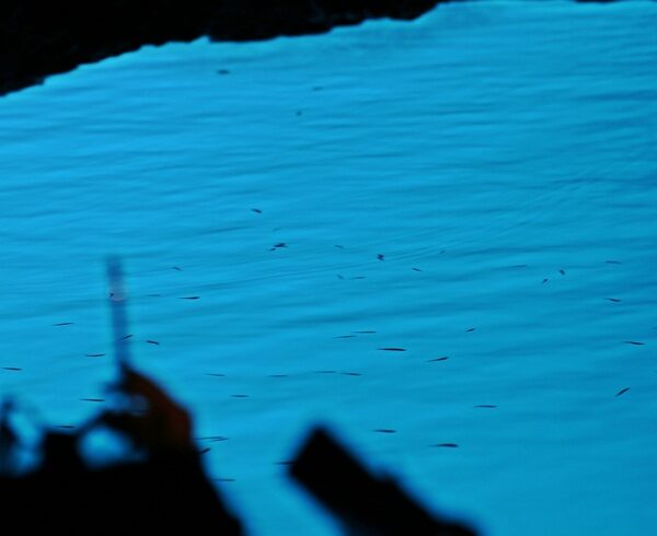 People taking pictures with phone inside the Blue Cave, Croatia.
