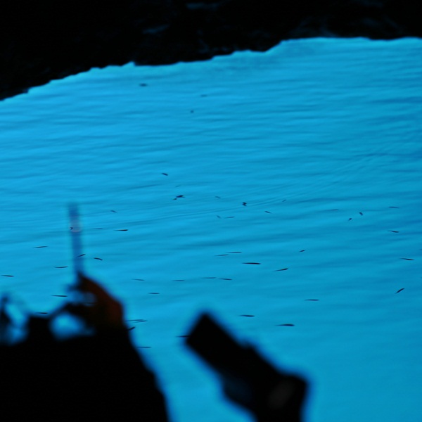People taking pictures with phone inside the Blue Cave, Croatia.